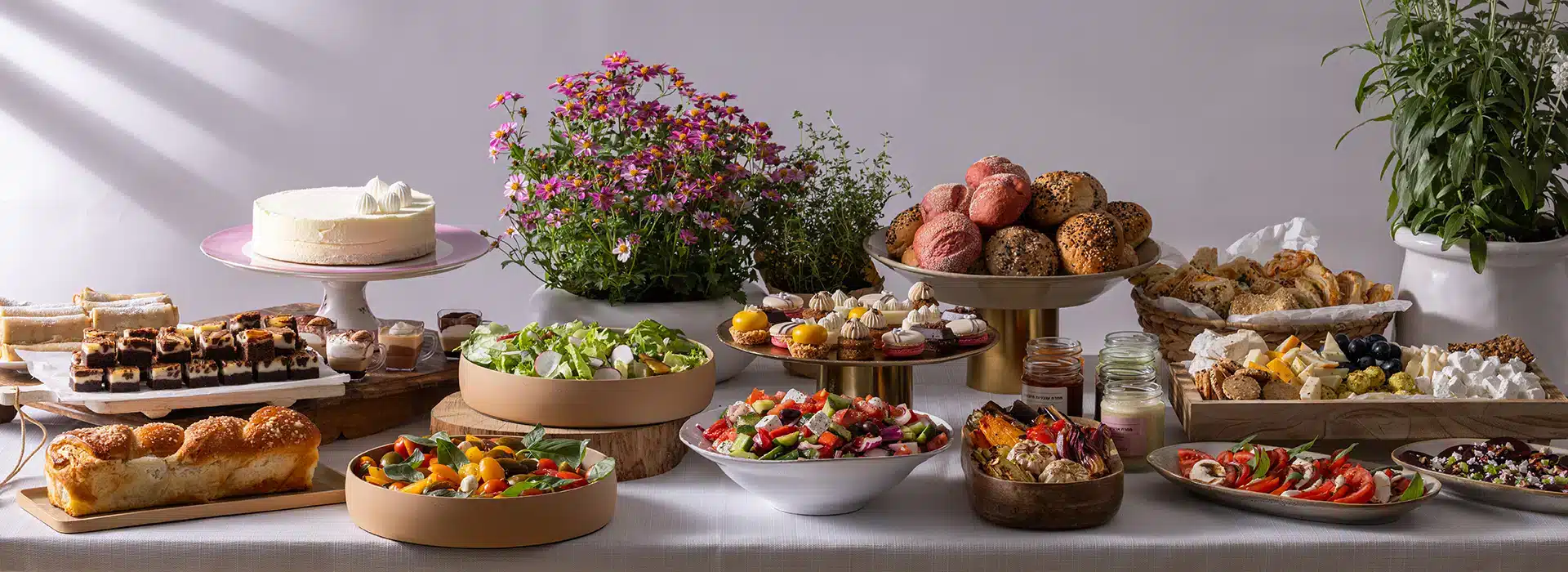 מגשי אירוח לשבועות עם גבינות, סלטים ומנות בעבודת יד